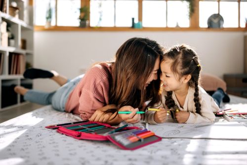 woman and young girl bonding while drawing laying on the floor - Guardian responsibilities concept