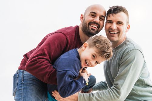 two dads smiling with their son - lgbtq adoption concept