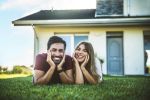 Happy young couple standing in front of new home - how to start estate planning concept
